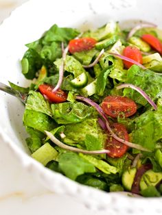 a salad in a white bowl with red onions and lettuce