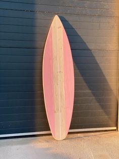 a pink surfboard leaning against a garage door