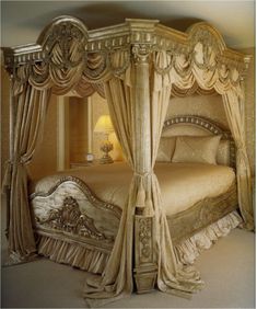 a fancy bed with curtains on the sides and pillows on the bottom, along with a night stand next to it