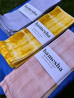 three different colored towels sitting on top of a blue cloth covered in white and yellow dye