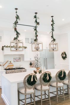 the kitchen is decorated for christmas with wreaths hanging from the ceiling and decorations on the island