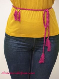 a woman wearing jeans and a yellow shirt with pink tassels on her waist