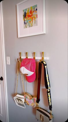 there are many purses hanging on the hooks in this room, and one is pink