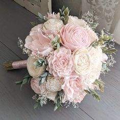 a bridal bouquet with pink and white flowers on a wooden floor in front of a door