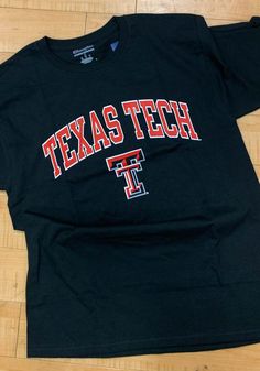 a black texas tech t - shirt on a wooden floor