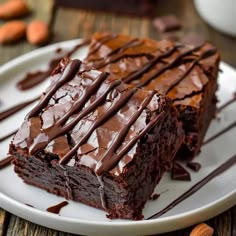 two pieces of chocolate cake sitting on top of a white plate next to almonds