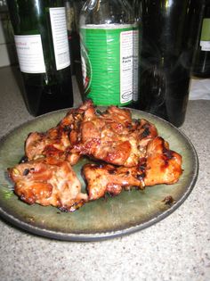 some chicken wings on a plate next to bottles of wine