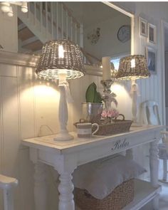 a table with two lamps on top of it and a basket under the table next to it