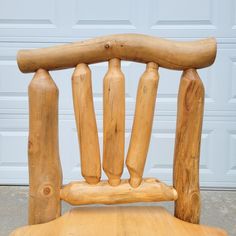 a wooden chair sitting on top of a cement floor next to a garage door,