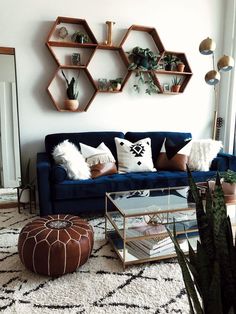 a living room with a blue couch and some shelves on the wall above it that are filled with plants