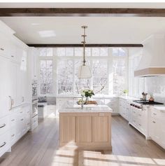 a large kitchen with white cabinets and wood flooring, along with an island in the middle