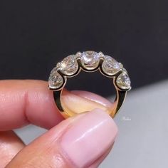 a person holding a gold ring with three diamonds on it's side and the middle finger