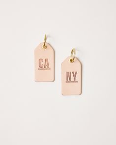 two tags with the words ca and ny hanging from each other on a white surface