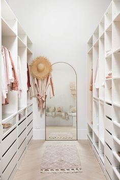 a walk in closet with white shelving and pink accessories on the shelves, along with an area rug