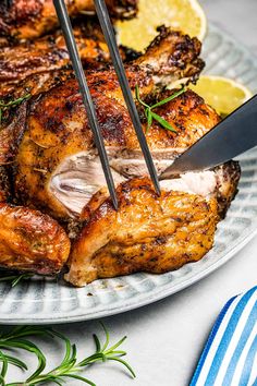 a close up of a chicken on a plate with a knife and some lemons