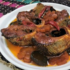 a white plate topped with meat covered in gravy and sauce on top of a colorful table cloth