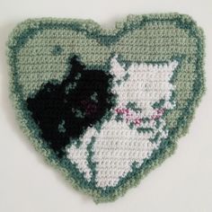 a crocheted heart with two cats on it