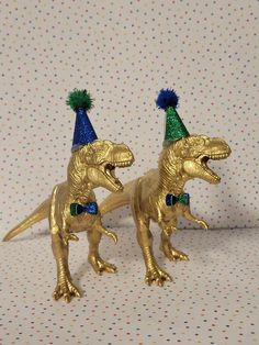 two gold dinosaur figurines wearing party hats