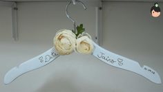 two white roses are hanging from a hanger with the words bride and groom written on it