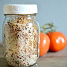 a glass jar filled with rice next to tomatoes