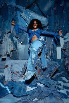 a woman is posing for a photo surrounded by denim jackets and jeans on the floor