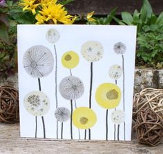 a card with dandelions on it sitting in front of some grass and flowers