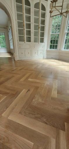 an empty room with wooden floors and white cabinets