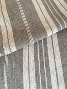 a close up view of the fabric on a bed with white and brown stripes in it