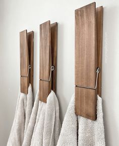 three towels are hanging on the wall with wooden hooks and towel holders attached to them