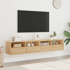 a living room with a large flat screen tv mounted on the wall next to a plant