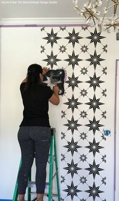 a woman is painting a wall with black and white designs