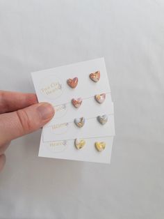 a person is holding several small heart shaped studs in their left hand and the other one has a sticker on it