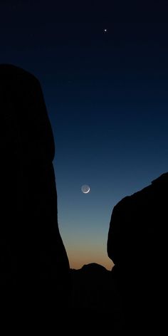 the moon is seen in the sky over some rocks