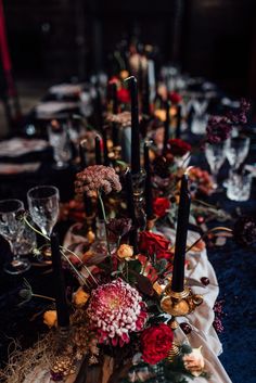 the table is set with candles, flowers and other items for an elegant dinner party