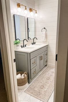 a bathroom with two sinks, mirrors and rugs on the floor in front of it