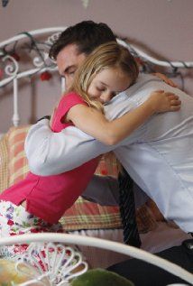 a man hugging a woman on top of a bed next to a bowl of fruit