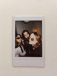 three women are taking a selfie in front of a wall with a light fixture