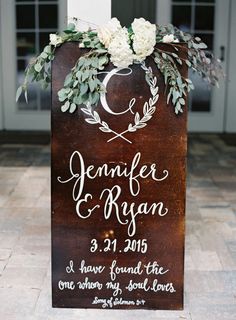 a wooden sign with white flowers and greenery on the top is featured in an instagram