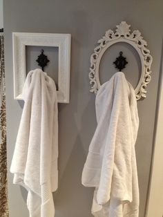 two white towels hanging on the wall next to a mirror