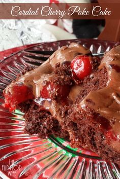 a piece of cake with chocolate frosting and cherries on top sitting on a glass plate