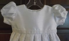 Esme is the perfect infant baptism, blessing, christening gown for an elegant event with your precious baby girl. The embroidered organza lace covering the skirt is extraordinary Esme is a long gown measuring 31 inches. Esme's basic fabric is a stunning white shantung. Esme has a high waist accented with a velvet ribbon. Esme has short puffed sleeves and 3 buttons in the back opening for easy dressing. Esme does not need a slip of skirt lining. This gown is light weight. NOTE: My sizes run large White Baptism Dress With Lace Bodice, Lace First Communion Dress With Fitted Bodice, Elegant First Communion Gown With Lace Sleeves, Elegant Gown With Lace Sleeves For First Communion, Elegant Baptism Dress With Lace Work, Elegant White Baptism Dress With Fitted Bodice, Elegant First Communion Dress With Lace Sleeves, White Lace Formal Gown, Fitted Baptism Dress With Lace Bodice