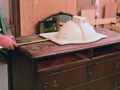 a person standing next to a wooden table with a hard hat on top of it