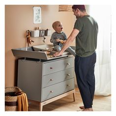 a man standing next to a child in a baby changing table with food on it