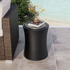 a table with a vase on it sitting next to a couch near the beach and water