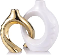 two white and gold vases sitting next to each other on a white table top