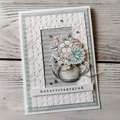 a handmade card with flowers in a teapot on top of a wooden table