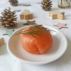 an orange piece of food on a white plate with pine cones and stars around it