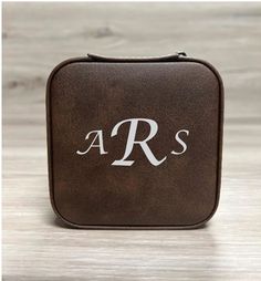 a brown leather case with the letter r and s in white on it, sitting on a wooden surface