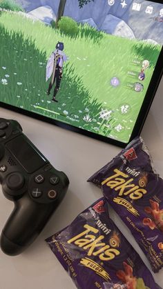 a video game controller sitting on top of a table next to two bags of chips