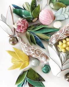 decorative ceramic flowers and leaves on a white surface with pearls, beads, and other items